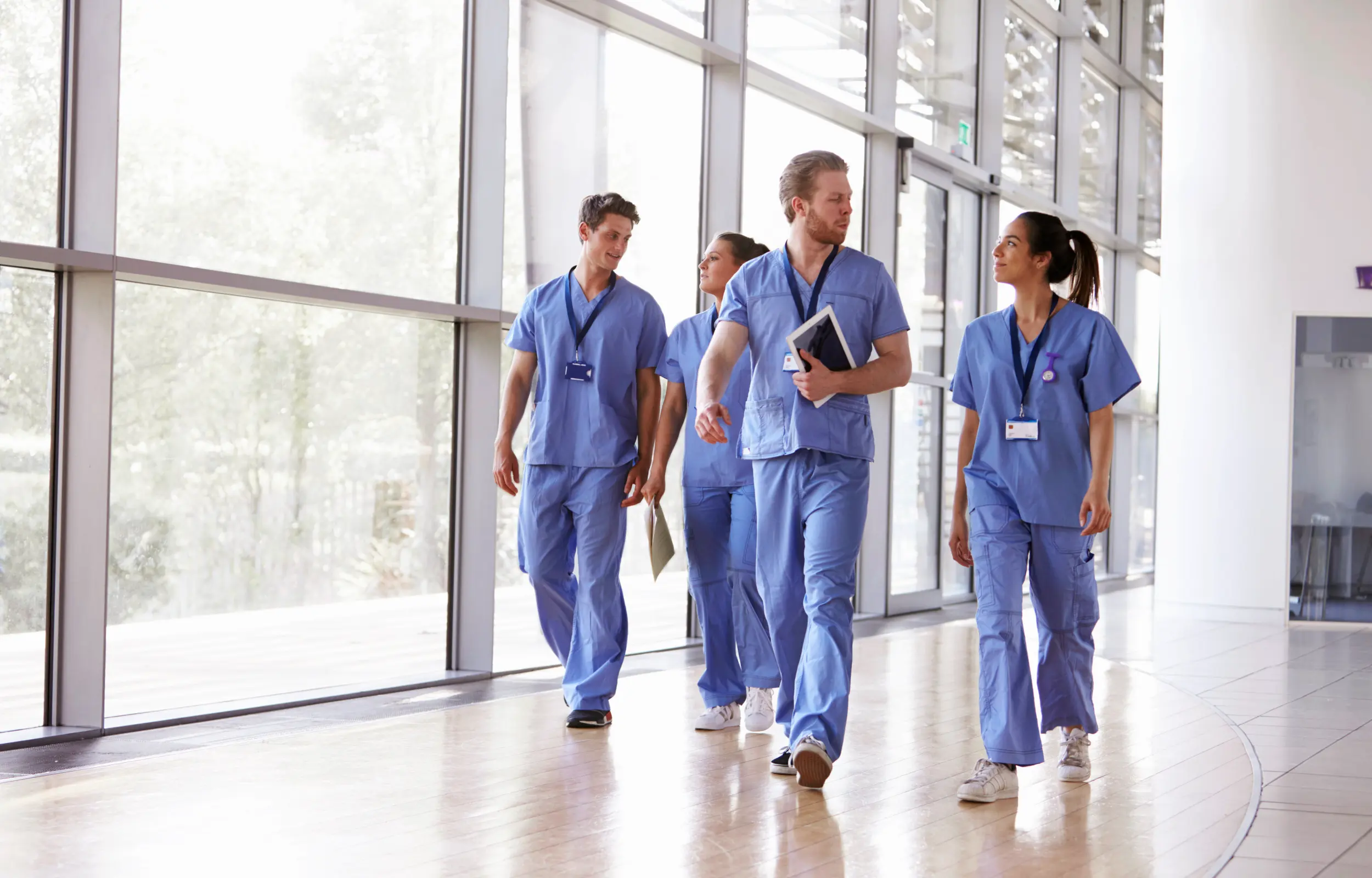 Médecin et infirmière discutant dans un hall d’hôpital avec vue sur arbre